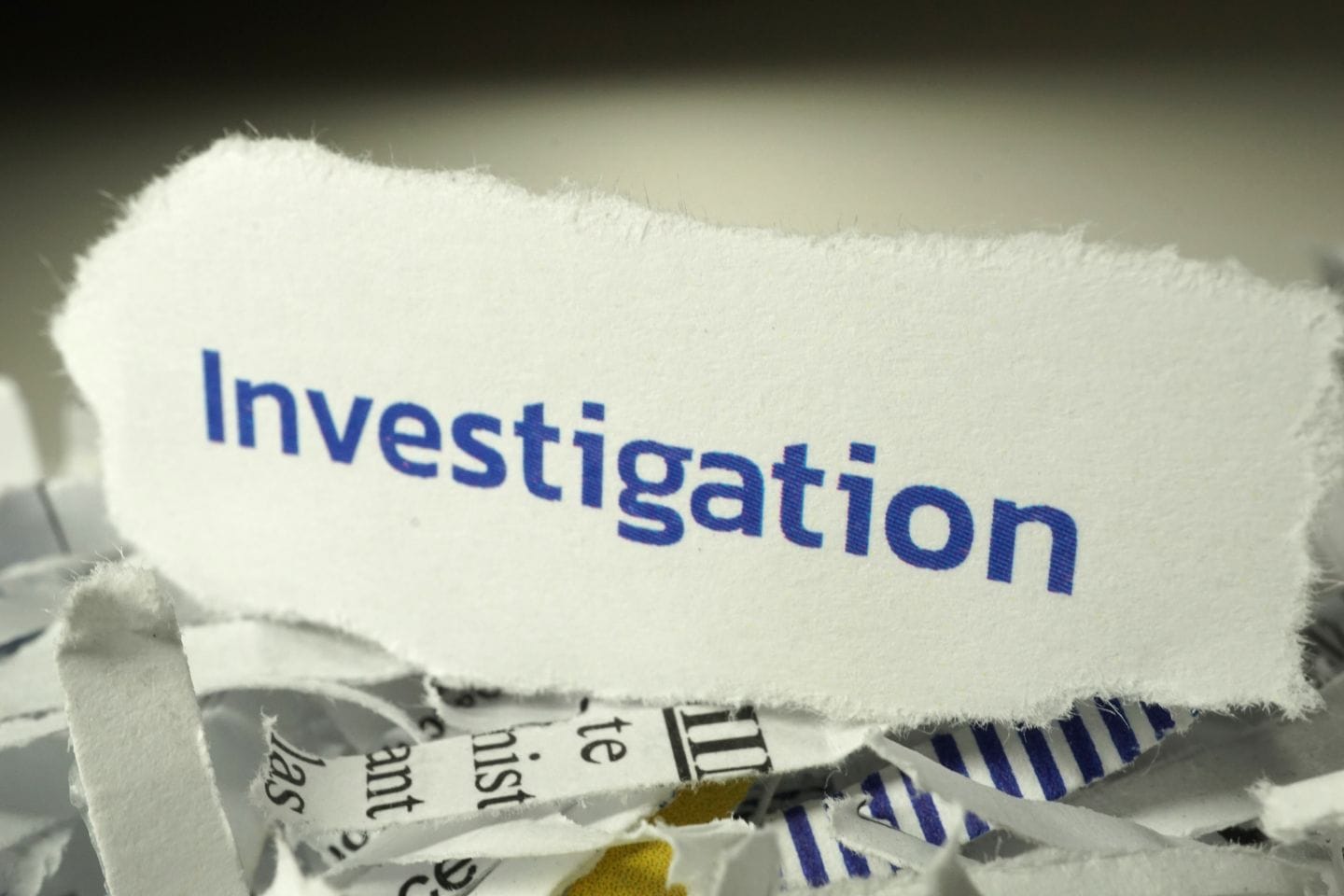 Torn paper with the word "Investigation" in blue text amid shredded paper.