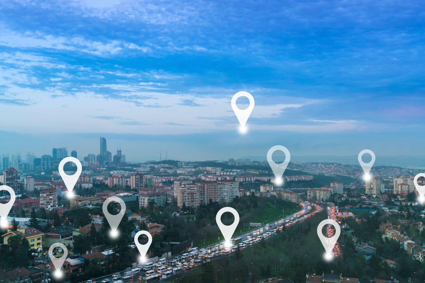 Cityscape with tall buildings under a blue sky, featuring location pin icons scattered throughout the scene.