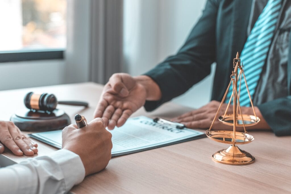 Two people sit at a table. One person signs a document while the other gestures, as if discussing the nuances of family law investigations. A gavel and scales of justice are visible, symbolizing the gravity and fairness of their deliberations.