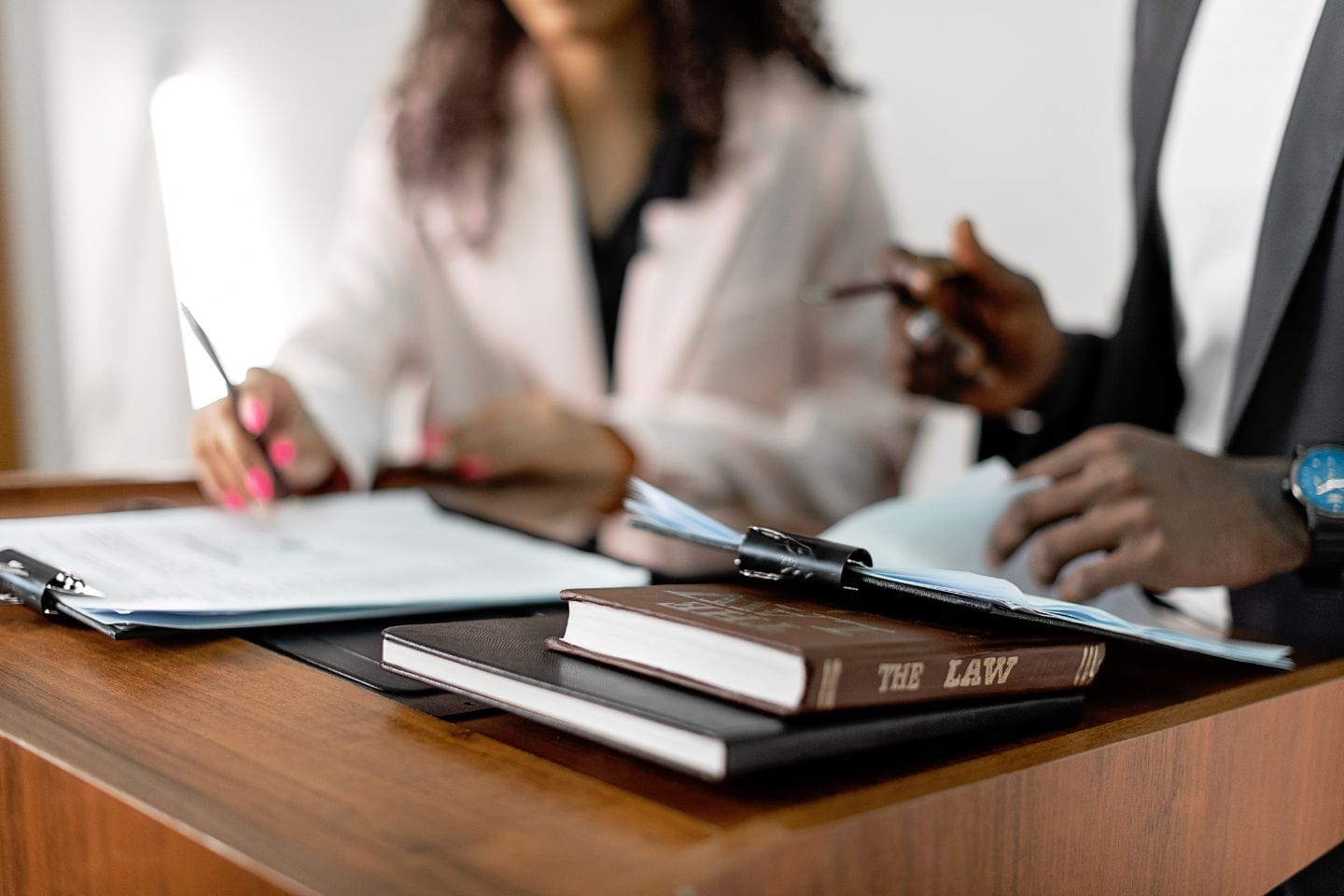 Two people are meticulously reviewing documents at a desk, surrounded by a law book focused on family law investigations.