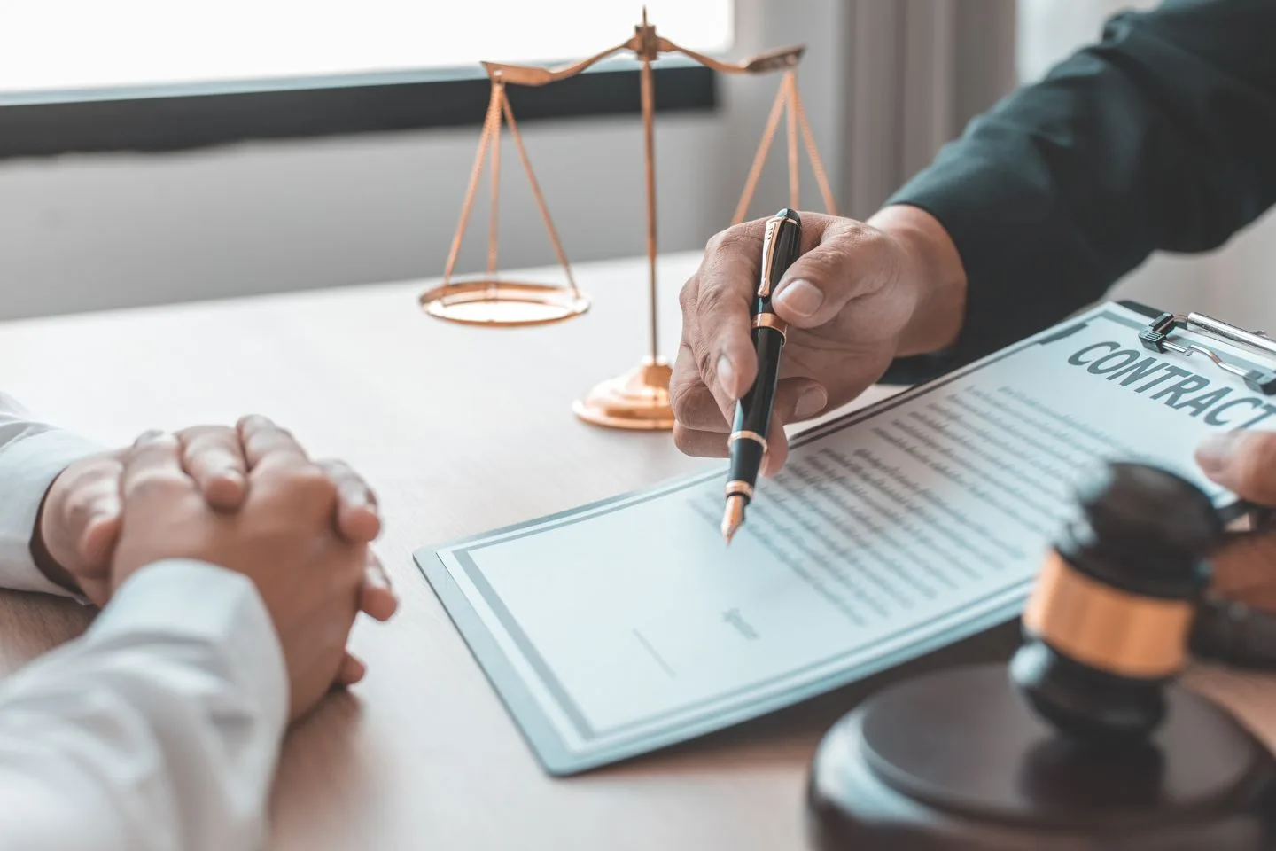 Civil and Criminal Litigation Support 13 Two people sit at a table discussing a contract, one pointing at the document with a pen. Nearby, a gavel and scales of justice symbolize the weight of family law investigations in this pivotal moment.