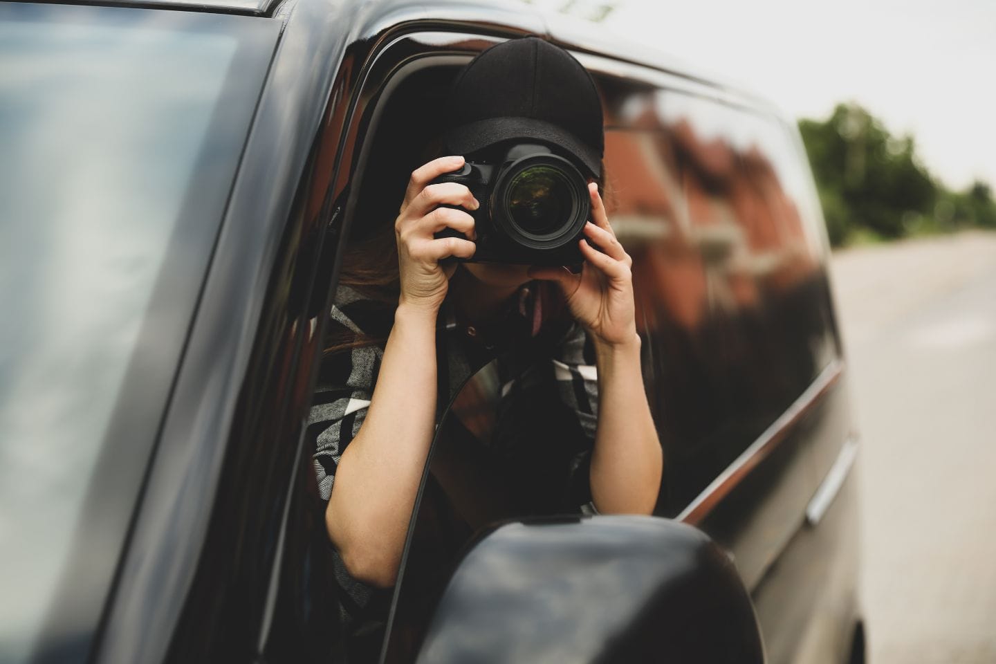 A person in a vehicle is holding a camera, capturing the world through the open window, much like seeking inspiration from the dynamic landscape of Technobiz.