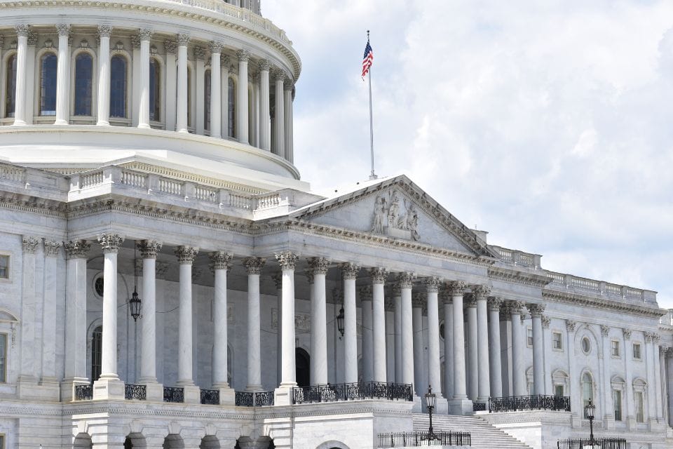 The U.S. Capitol building, with its grand columns and dome, serves as an enduring symbol of democracy, featuring a flag flying atop the structure.