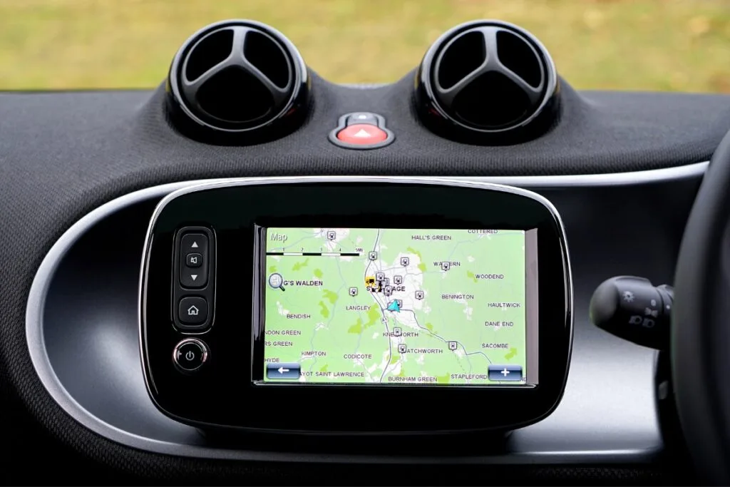 Identifying Issues With Your Current GPS Tracking System 3 The car dashboard features a sophisticated GPS tracking system with a navigation screen displaying a map. Above the screen are two circular air vents, while an array of control buttons lines the left side, ensuring seamless access to all essential functions.
