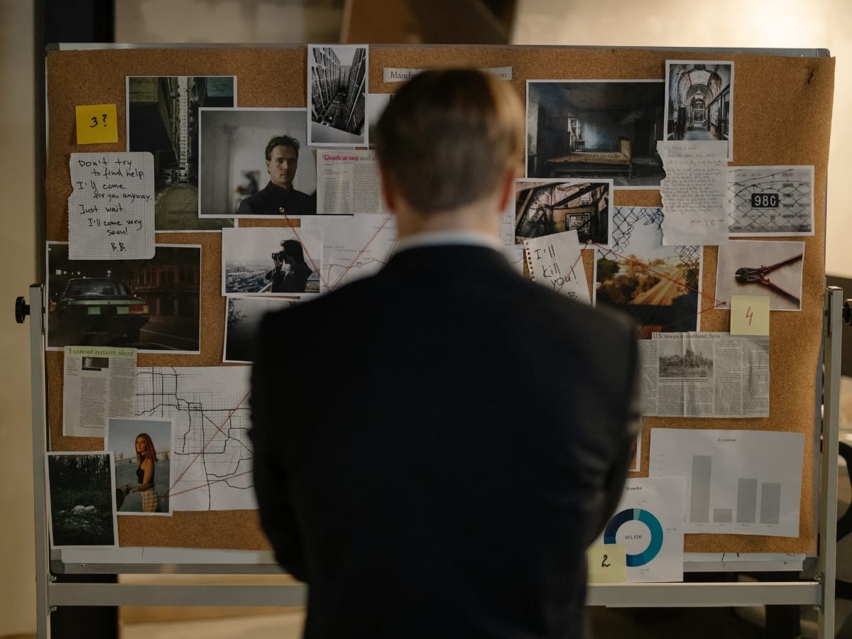 A man in a suit stands facing a corkboard covered with photos, notes, maps, and documents arranged to illustrate the Private Investigation Process.