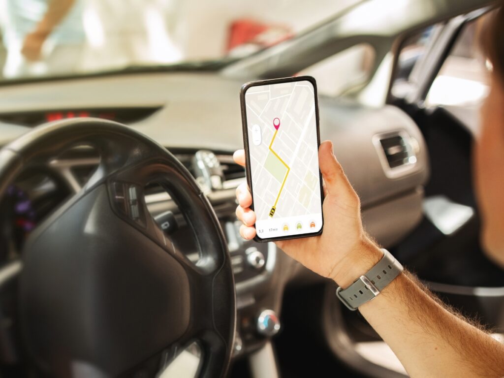 GPS Tracking for Investigations & Asset Recovery 7 A person in a car holds a smartphone displaying a GPS navigation map with GPS tracking and the route clearly highlighted on the screen.